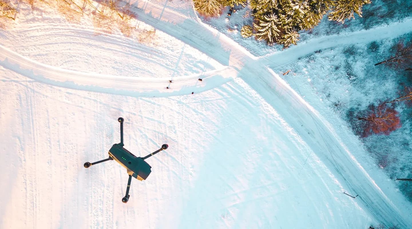 A quadcopter drone flying over a snowy landscape, surveying terrain from above